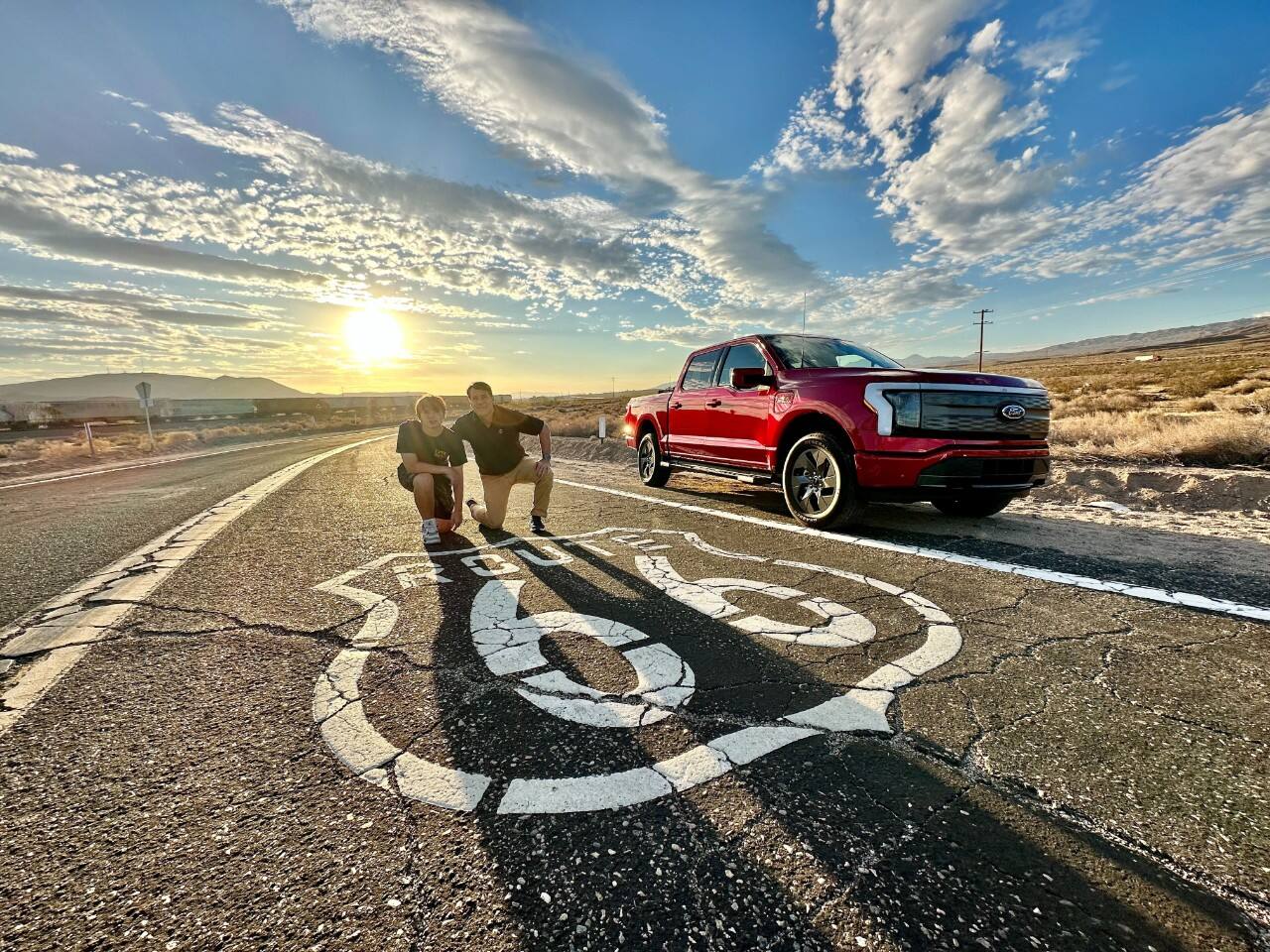 Jim and Jameson Farley pose by a road sign for Route 66, with Jim’s F-150 Lightning behind them.